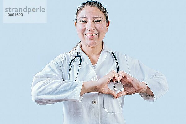 Lächelnder Arzt macht Herzform auf isoliertem Hintergrund. Freundliche Ärztin macht Herz Geste mit Händen isoliert