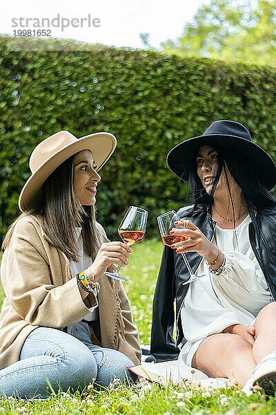 Porträt von zwei lustigen Freunden  die sich beim Weintrinken und Lachen im Park amüsieren