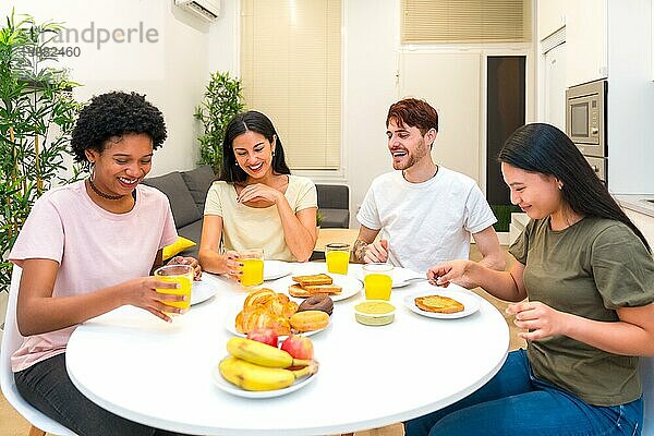 Glückliche Freunde  die gemeinsam an einem Tisch in der Wohnung ein gesundes Frühstück zu sich nehmen