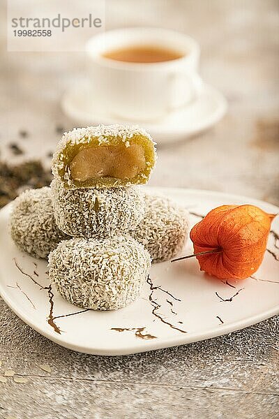 Japanischer Reis süße Brötchen Mochi gefüllt mit Pandan Marmelade und Tasse grüner Tee auf braunem Beton Hintergrund. Seitenansicht  Nahaufnahme  selektiver Fokus