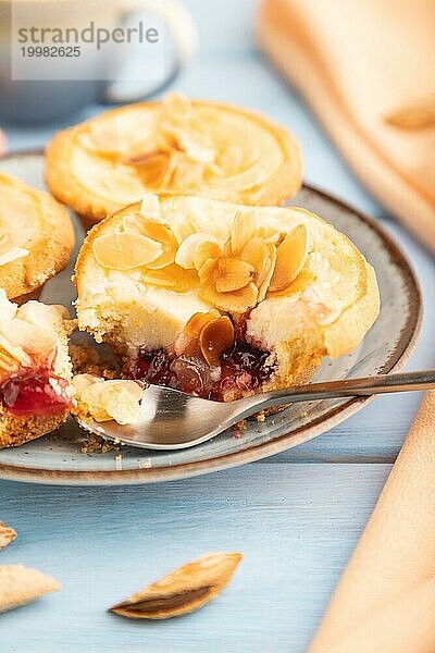 Traditionelle portugiesische Kuchen Pasteis de Nata  Pudding kleine Kuchen mit Mandeln mit Tasse Kaffee auf blauem hölzernen Hintergrund und orange Textil. Seitenansicht  Nahaufnahme  selektiver Fokus