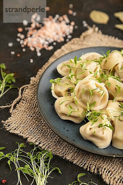 Knödel mit Pfeffer  Salz  Kräutern  Mikrogrün auf schwarzem Betonhintergrund und Leinenstoff. Seitenansicht  Nahaufnahme  selektiver Fokus