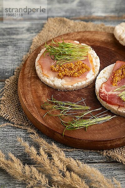 Puffreiskuchen Sandwiches mit Jerky Salzfleisch  Karotten Mikrogrün auf grauem Holzhintergrund und Leinenstoff. Seitenansicht  Nahaufnahme  selektiver Fokus