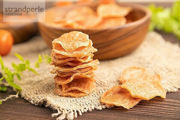 Scheiben von dehydrierten gesalzenen Fleischchips mit Kräutern und Gewürzen auf braunem Holzhintergrund und Leinenstoff. Seitenansicht  Nahaufnahme  selektiver Fokus