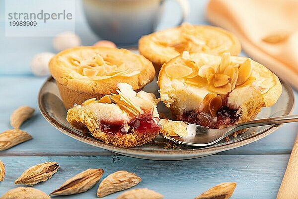 Traditionelle portugiesische Kuchen Pasteis de Nata  Pudding kleine Kuchen mit Mandeln mit Tasse Kaffee auf blauem hölzernen Hintergrund und orange Textil. Seitenansicht  Nahaufnahme  selektiver Fokus