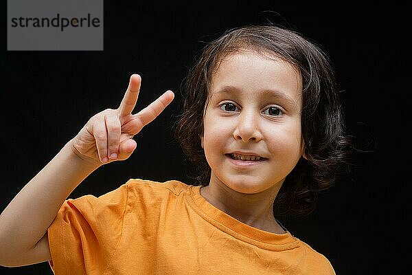 Lächelndes Kind mit glücklichem Gesicht  das eine Friedensgeste macht und siegt