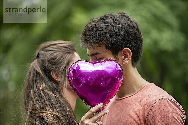 Küssendes Paar  bedeckt von einem herzförmigen Ballon