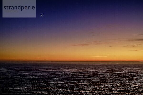 Schöne ruhige Blick auf den Ozean bei Sonnenuntergang  mit einem Farbverlauf von orange bis lila und eine Mondsichel in den Himmel. Bunte klaren Himmel in der Dämmerung  Horizont über Wasser  ruhige Gewässer. Meereslandschaft im Hintergrund