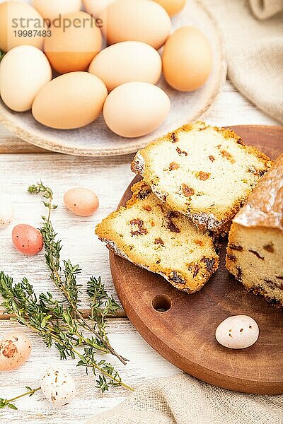 Hausgemachter Osterkuchen mit Rosinen und Eiern auf einem Teller auf einem weißen hölzernen Hintergrund und Leinenstoff. Seitenansicht  Nahaufnahme  selektiver Fokus