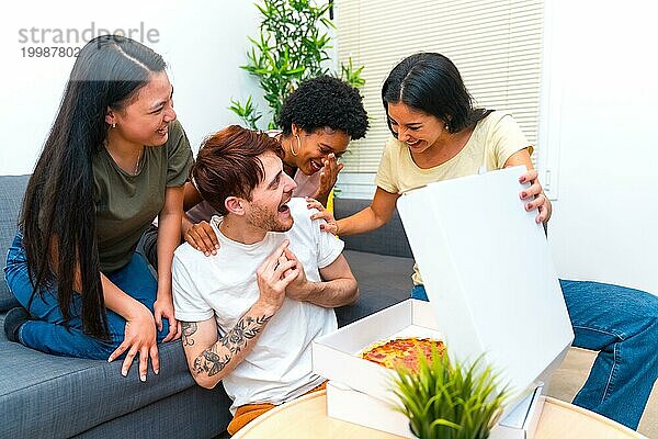 Glückliche und hungrige junge multiethnische Freunde  die eine Pizza geliefert bekommen