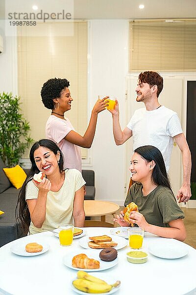 Vertikales Foto einer Gruppe multiethnischer Freunde  die beim Frühstück zu Hause genießen und feiern