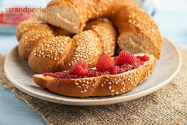 Hausgemachte süße Brötchen mit Himbeermarmelade und eine Tasse Kaffee auf einem blauen hölzernen Hintergrund und Leinenstoff. Seitenansicht  Nahaufnahme  selektiver Fokus