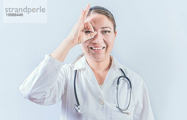 Junge Ärztin  die mit dem Finger auf einem isolierten Hintergrund zustimmt. Fröhliche Ärztin gestikuliert Zustimmung isoliert