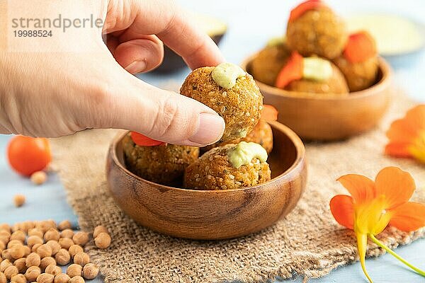 Falafel mit Guacamole auf blauem Holzhintergrund und Leinentextil mit Hand. Seitenansicht  Nahaufnahme  selektiver Fokus