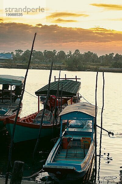 Traditionelle hölzerne Fischerboote der Khmer  die bei Sonnenuntergang am ruhigen Fluss vertäut sind  zeigen das offene  friedliche Alltagsleben in Kampot  Kambodscha  Asien