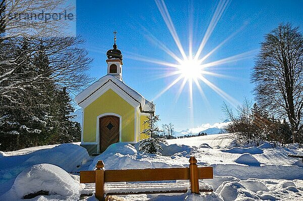 Gegenlichtaufnahme der verschneiten Kapelle Maria auf den Buckelwiesen Werdenfelser Land bei Garmisch in winterlicher Idylle  im Hintergrund das Karwendelgebirge  Bayern  Deutschland  Europa