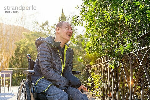 Porträt eines glücklichen behinderten Mannes  der an einem sonnigen Tag in einem Stadtpark über die Natur nachdenkt  aus niedriger Perspektive