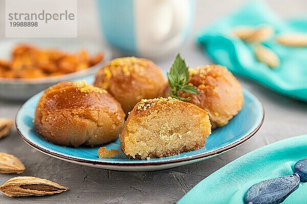 Hausgemachtes traditionelles türkisches Dessert Sekerpare mit Mandeln und Honig  Tasse grüner Tee auf grauem Betonhintergrund und blauem Textil. Seitenansicht  selektiver Fokus