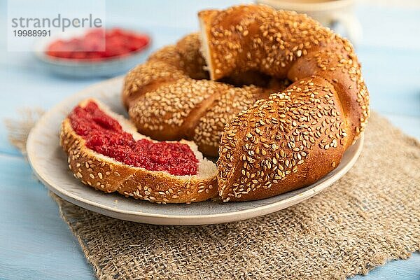 Hausgemachte süße Brötchen mit Himbeermarmelade und eine Tasse Kaffee auf einem blauen hölzernen Hintergrund und Leinenstoff. Seitenansicht  Nahaufnahme  selektiver Fokus