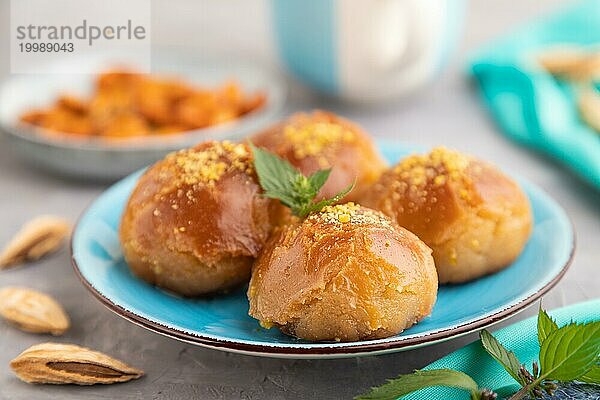 Hausgemachtes traditionelles türkisches Dessert Sekerpare mit Mandeln und Honig  Tasse grüner Tee auf grauem Betonhintergrund und blauem Textil. Seitenansicht  selektiver Fokus