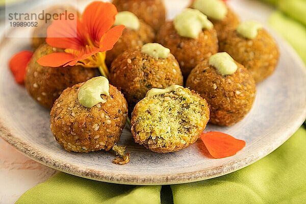 Falafel mit Guacamole auf weißem Betonhintergrund und grünem Leinentuch. Seitenansicht  Nahaufnahme  selektiver Fokus