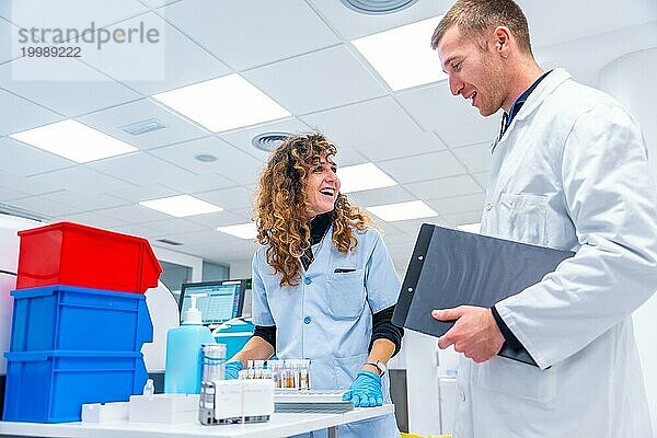 Fröhliche junge Wissenschaftler bei der Arbeit mit Proben in einem pathologischen Forschungslabor in einem Krankenhaus