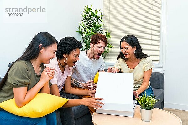 Glückliche multirassische Freunde sitzen auf einer Couch und öffnen einen Pizzakarton  um zu Hause zu essen