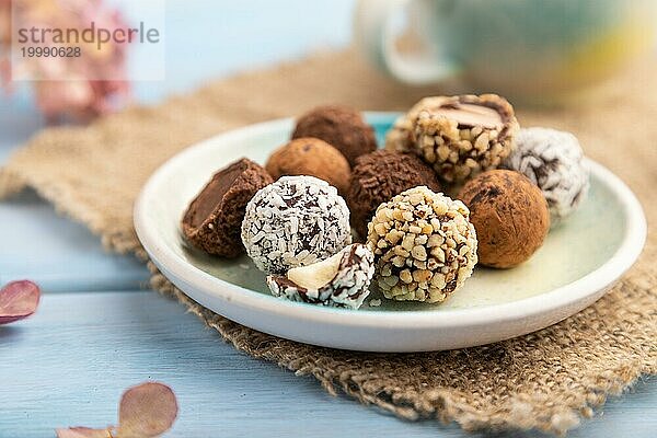 Schokoladen Trüffel Bonbons mit einer Tasse Kaffee auf einem blauen Holzhintergrund und Leinenstoff. Seitenansicht  Nahaufnahme  selektiver Fokus