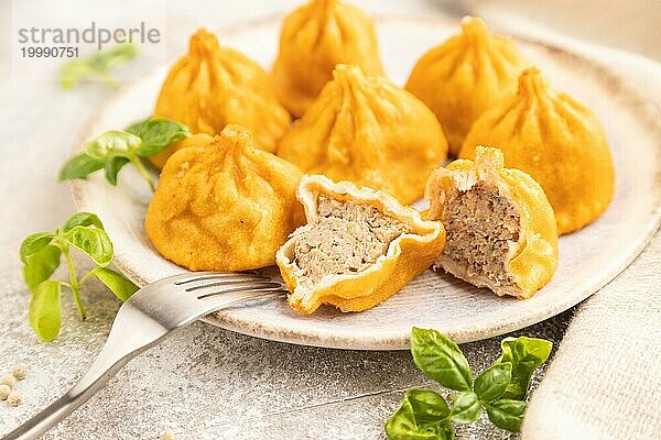 Gebratene Manti Knödel mit Pfeffer und Basilikum auf grauem Betonhintergrund und Leinenstoff. Seitenansicht  Nahaufnahme  selektiver Fokus