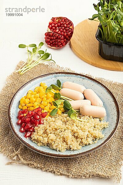 Gemischter Quinoa Brei  süßer Mais  Granatapfelkerne und kleine Würstchen auf weißem Holzhintergrund. Seitenansicht  Nahaufnahme. Essen für Kinder  gesundes Essen Konzept