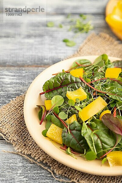 Vegetarischer Gemüsesalat aus gelber Paprika  Rüben und mikrogrünen Sprossen auf grauem Holzhintergrund und Leinentuch. Seitenansicht  Nahaufnahme  selektiver Fokus