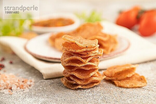 Scheiben von dehydrierten gesalzenen Fleischchips mit Kräutern und Gewürzen auf grauem Betonhintergrund und weißem Textil. Seitenansicht  Nahaufnahme  selektiver Fokus