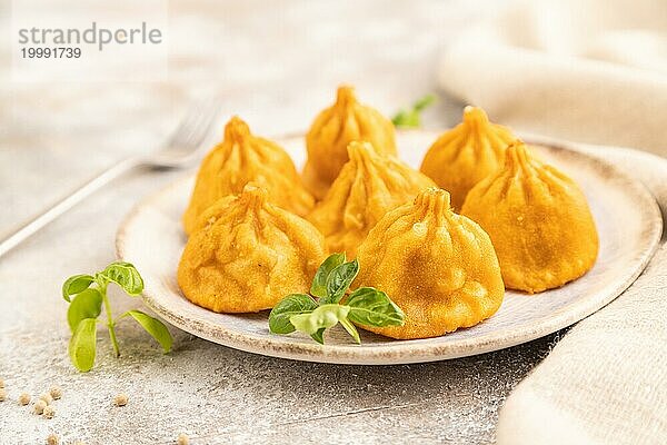 Gebratene Manti Knödel mit Pfeffer und Basilikum auf grauem Betonhintergrund und Leinenstoff. Seitenansicht  Nahaufnahme  selektiver Fokus