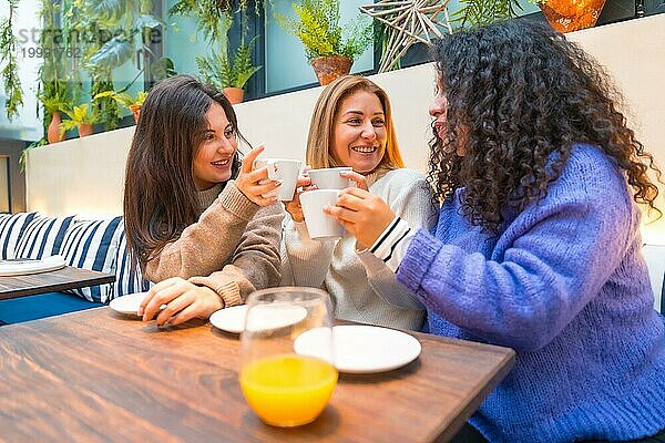 Drei erwachsene kaukasische Frauen unterhalten sich fröhlich in einer bunten Cafeteria