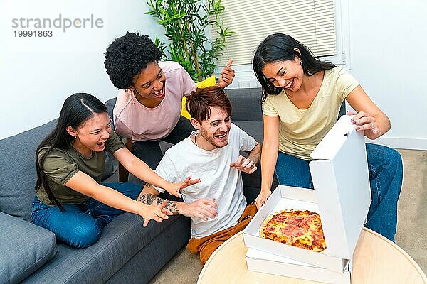 Multiethnische  ausgehungerte Freunde  die bereit sind  gemeinsam im heimischen Wohnzimmer eine Lieferpizza zu essen