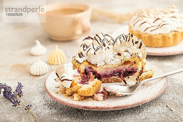 Zwei Törtchen mit Baisercreme und Tasse Kaffee auf braunem Betonhintergrund. Seitenansicht  selektiver Fokus. Frühstück  Morgen  Konzept