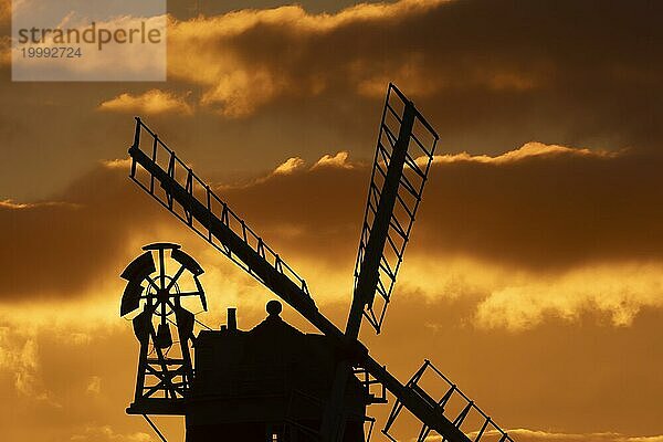 Windmühle als Silhouette bei Sonnenuntergang mit rotem Himmel und Wolken dahinter  Cley next to the sea  Norfolk  England  Großbritannien  Europa