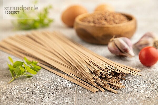 Japanische Buchweizen Soba Nudeln mit Tomaten  Eiern  Gewürzen  Kräutern auf braunem Betonhintergrund. Seitenansicht  Nahaufnahme  selektiver Fokus