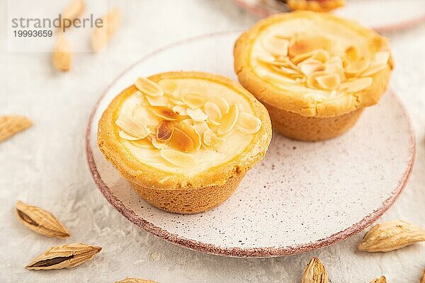 Traditionelle portugiesische Kuchen pasteis de nata  Pudding kleine Kuchen mit Mandeln mit Tasse Kaffee auf grauem Beton Hintergrund. Seitenansicht  Nahaufnahme  selektiver Fokus