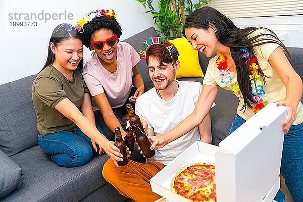 Freunde feiern Geburtstag mit Pizza und Bier und stoßen gemeinsam im Wohnzimmer an