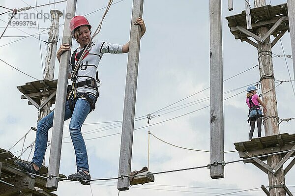 Junges Mädchen im Kletterpark  klettern  Aktion  Sicherheit  Sicherung  Absichern  Sicherungsseil  Sicherrungstechnik  Sicherungshaken  Mut  mutig  Freizeit  Hobby  Höhe  Höhenangst  Überwindung  Sport
