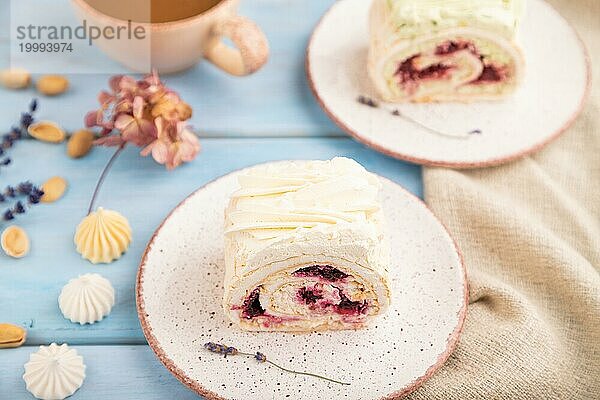 Biskuitrolle mit Frischkäse und Marmelade  Tasse Kaffee auf blauem Holzhintergrund und Leinenstoff. Seitenansicht  Nahaufnahme  selektiver Fokus