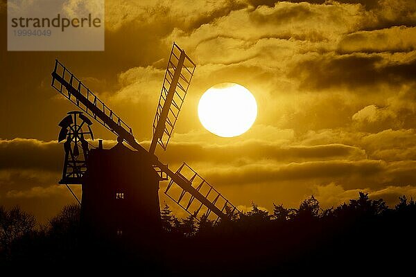 Windmühle als Silhouette bei Sonnenuntergang mit rotem Himmel und Wolken dahinter  Cley next to the sea  Norfolk  England  Großbritannien  Europa