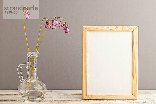 Holzrahmen mit rosa Dicentra  gebrochenes Herz im Glas auf grauem Pastell Hintergrund. Seitenansicht  Kopierraum  Mockup  Vorlage  Frühling  Sommer Minimalismus Konzept