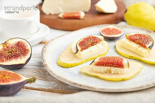 Sommerliche Vorspeise mit Birne  Hüttenkäse  Feigen und Honig auf einem weißen Holzhintergrund und Leinenstoff. Seitenansicht  Nahaufnahme  selektiver Fokus