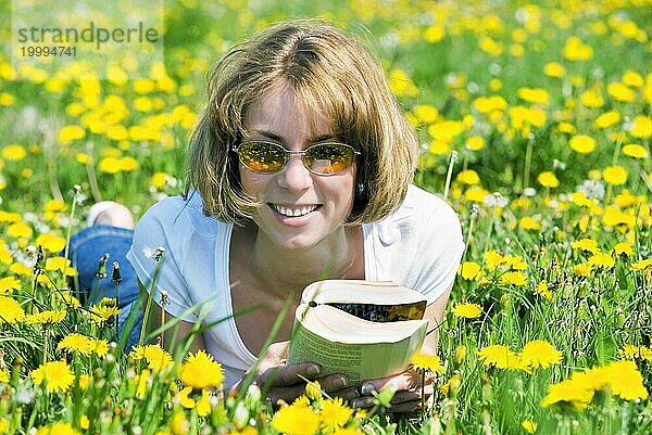 Junge Frau auf Blumenwiese liest ein Buch