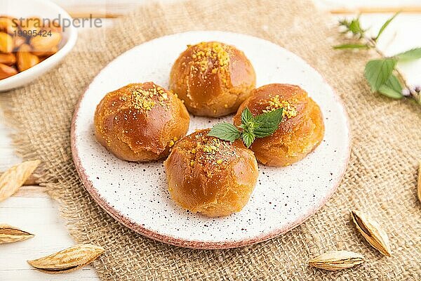 Hausgemachtes traditionelles türkisches Dessert Sekerpare mit Mandeln und Honig  Tasse grüner Tee auf weißem Holzhintergrund und Leinenstoff. Seitenansicht  Nahaufnahme  selektiver Fokus