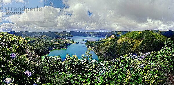 Malerischer Panoramablick auf die Kraterseen Lagoa Verde und Lagoa Azul umgeben von grünen Kraterrändern und blühenden Hydrangea unter einem heiteren Himmel  Krater Rundwanderweg  Caldeira das Sete Cidades  Miradouro da Vista do Rei  Lagoa Verde  Lagoa Azul  Sao Miguel  Portugal  Europa