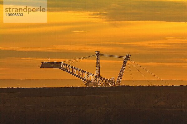 Silhouette einer großen Förderbrücke gegen den orange gefärbten Abendhimmel  Braunkohle-Tagebau  Nordrhein-Westfalen  Deutschland  Europa