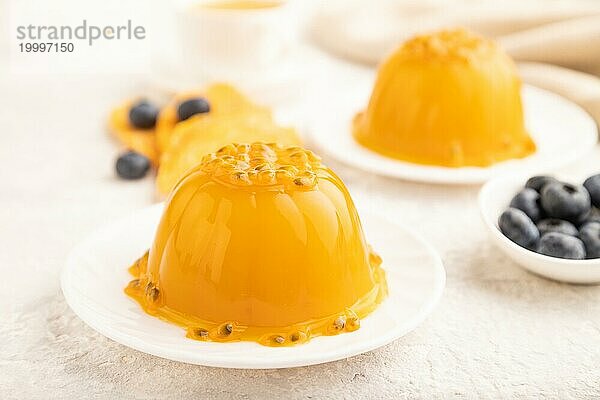 Mango und Maracuja Gelee mit Heidelbeeren auf grauem Betonhintergrund und Leinentextil. Seitenansicht  Nahaufnahme  selektiver Fokus